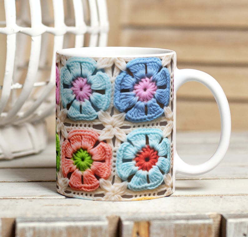 Puede incluir: Taza de cer&aacute;mica blanca con un dise&ntilde;o de flores de ganchillo de colores. Las flores son en tonos de rosa, azul, verde y naranja.