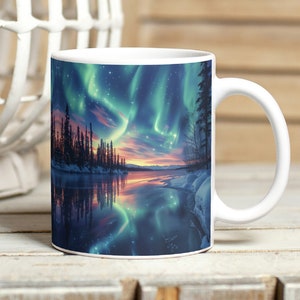 May include: White ceramic mug with a colorful image of the aurora borealis reflected in a lake with a forest in the background.