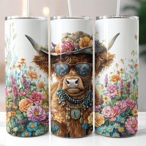 May include: A white tumbler featuring a watercolor illustration of a Highland cow wearing sunglasses, a hat adorned with flowers, and a beaded necklace. The design is surrounded by colorful wildflowers and greenery, with a straw.