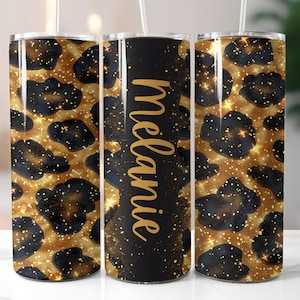 Könnte beinhalten: Ein personalisierter Becher mit einem gold-schwarzen Leopardenmuster. Der Becher trägt den Namen "Melanie" in goldener Schrift auf schwarzem Hintergrund. Enthält einen weißen Strohhalm.