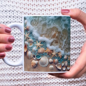 May include: White ceramic mug with a beach scene printed on it. The scene features a foamy wave crashing on the shore with seashells and blue glass scattered on the sand.