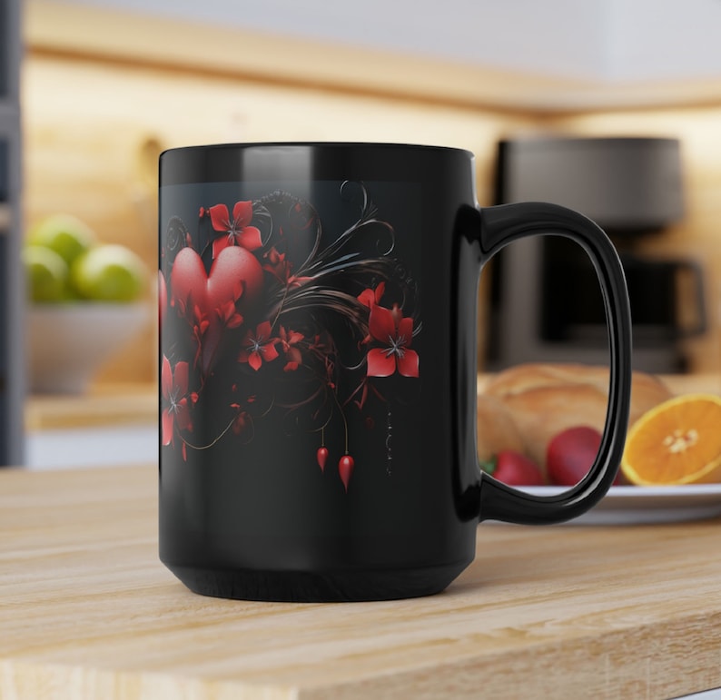 May include: Black ceramic coffee mug with a red heart and floral design. The design features a large red heart with intricate black swirls and red flowers.