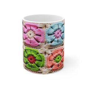 Puede incluir: Una taza de cer&aacute;mica blanca con un dise&ntilde;o de ganchillo colorido. El dise&ntilde;o presenta cuatro cuadrados con flores de diferentes colores en el centro de cada cuadrado. Las flores son rosas, azules, verdes y naranjas.