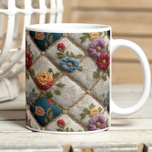 以下が含まれることがあります： 赤、青、黄、紫の花が描かれたキルト風のフローラルデザインが特徴の白いセラミックマグ。デザインには、フローラルパターンが施されたターコイズの正方形が含まれています。マグには白いハンドルが付いています。