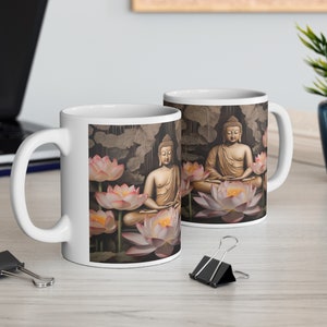 May include: Two white ceramic mugs with a design of two golden Buddhas meditating on lotus flowers. The background is a dark brown with a pattern of leaves.
