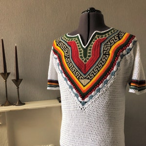 May include: White crochet top with a colourful geometric pattern around the neckline and hem. The pattern features red, yellow, green, and blue stripes.