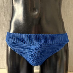May include: Blue crocheted swim briefs on a mannequin.