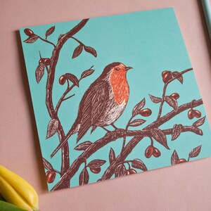 May include: A robin perched on a branch with red berries against a turquoise background. The robin is brown with a red breast and is depicted in a vintage style.