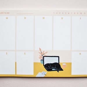 May include: A beige weekly planner notepad with a black cat sleeping on a laptop. The notepad has a yellow border and the days of the week are labelled with the first letter of each day. The notepad has the text "I LOVE TO DO" at the top.