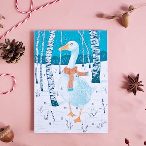 May include: A rectangular advent calendar featuring a white goose wearing an orange knit scarf standing in a snowy birch forest. The illustration includes numbered countdown slots from 1 to 24 scattered across the scene in a blue and white color palette.