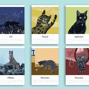 May include: A wall calendar featuring six monthly pages from July to December, each displaying a unique illustration of a cat in various settings, including outdoor scenes, indoor play, and mirror reflections, with printed month names and dates.