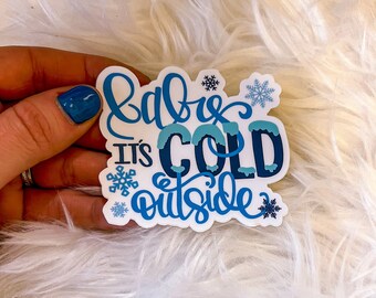 May include: White sticker with blue lettering that reads "Baby, it's cold outside" with snowflakes.
