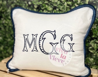 May include: White pillow with a navy blue trim and the letters "MGG" embroidered in navy blue.