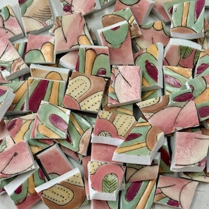 May include: A collection of broken ceramic tiles with abstract designs in shades of pink, green, yellow, and brown. The tiles have a variety of shapes and sizes, with some featuring dotted patterns and curved lines. The overall aesthetic is artistic and colorful.