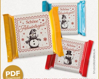 Op de afbeelding: Drie chocoladereepverpakkingen met een winterthema. Elke verpakking heeft een sneeuwpopillustratie en de tekst "Schöne Adventszeit!". De verpakkingen zijn geel, blauw en rood, met een PDF-downloadoptie.
