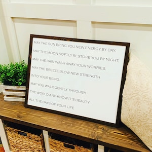 May include: A white framed sign with a black background and white text. The text reads: "May the sun bring you new energy by day. May the moon softly restore you by night. May the rain wash away your worries. May the breeze blow new strength into your being. May you walk gently through the world and know it's beauty all the days of your life."