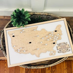 May include: A wooden map of the United States with a list of stadiums to visit. The map is framed and has a sign that says "The Stewart Stadium Bucket List".
