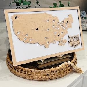 May include: A wooden map of the United States with a cutout of each NFL stadium. The map is framed in wood and has a small plaque that reads "The Bridges NFL Stadium List".