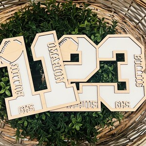 May include: Three layered wooden cutout numbers 1, 1, and 3 featuring white inserts. The number 1 includes the text Bulldog and GHS. The number 1 features the name Omarion. The number 3 displays the text Bulldog and GHS, with Darius visible below.
