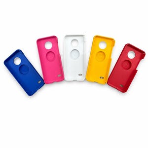Könnte beinhalten: Ein Set aus fünf rechteckigen Smartphone-Hüllen, die fächerförmig angeordnet sind. Die Hüllen sind blau, pink, weiß, gelb und rot. Jede Hülle verfügt über einen kreisförmigen Ausschnitt für ein Kameraobjektiv und eine kleinere Vertiefung.