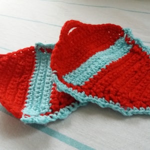 May include: Two crocheted pot holders in red and blue. The pot holders are triangular in shape and have a loop at the top for hanging.
