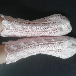 May include: A pair of pink knitted socks with a lacy pattern. The socks have a scalloped edge.