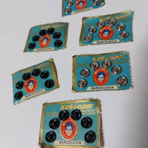 May include: Six cards of black metal snap fasteners with the Koh-i-noor brand name and a logo of a man's face. The cards are blue and gold with the text "Koh-i-noor" and "Barcelona" printed on them.