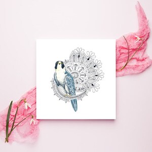 May include: A black and white mandala design with a blue and gray falcon in the center. The falcon is facing to the right and has a yellow beak and black eyes.