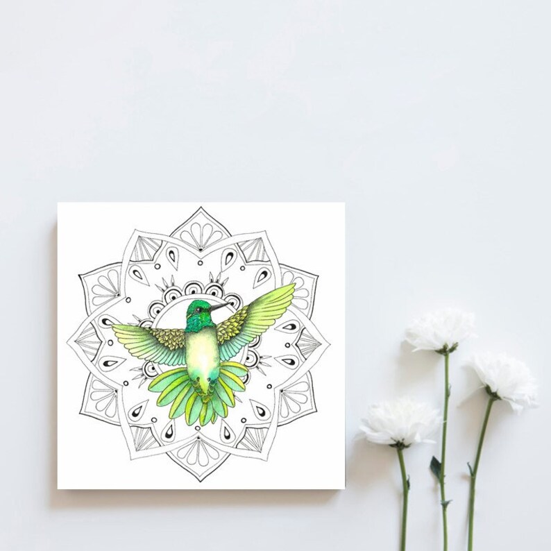 May include: A green and yellow hummingbird with outstretched wings is flying in the center of a black and white mandala. The mandala is a circular design with intricate patterns.