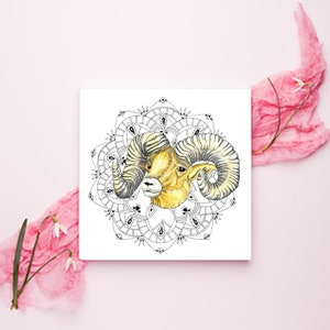 May include: A black and white mandala design with a yellow and brown ram head in the center. The ram has large curled horns.