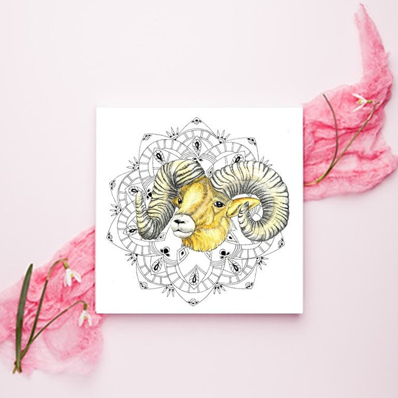 May include: A black and white mandala design with a yellow and brown ram head in the center. The ram has large curled horns.