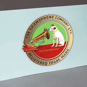 May include: A circular logo with a gold border and a white dog sitting next to a gramophone. The logo reads "The Gramophone Company Ltd." and "His Master's Voice" in a red banner. The logo also says "Registered Trade Mark" around the bottom.