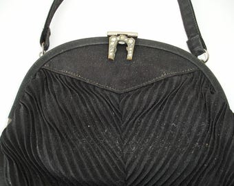 May include: A black pleated fabric handbag with a silver clasp and a silver chain strap.