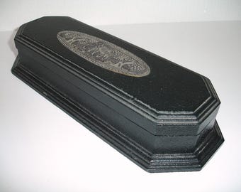 May include: A black wooden box with a silver embossed design on the top. The box has a hinged lid and a rectangular shape.