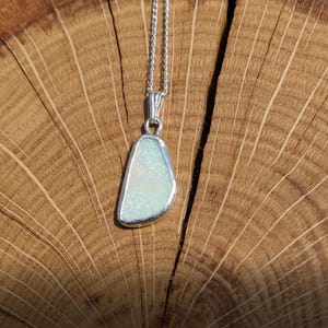 May include: A silver chain necklace with a pendant featuring a white opal stone set in a silver bezel.