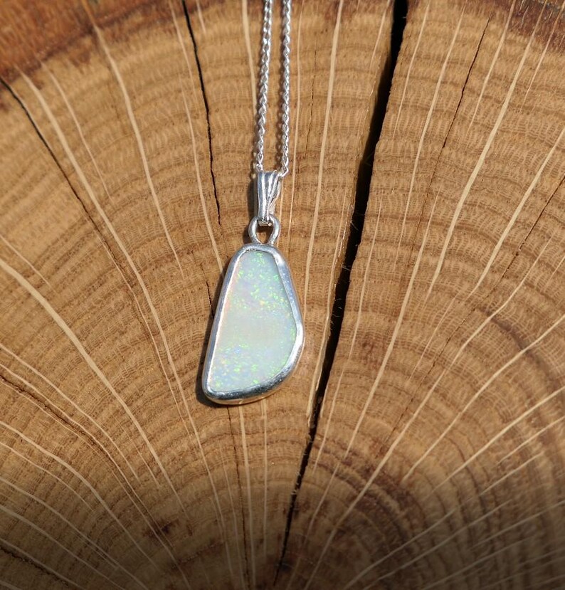 May include: A silver chain necklace with a pendant featuring a white opal stone set in a silver bezel.