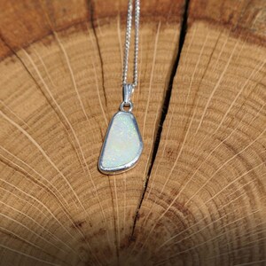 May include: A silver chain necklace with a white opal pendant. The pendant is a freeform shape and has a silver setting.
