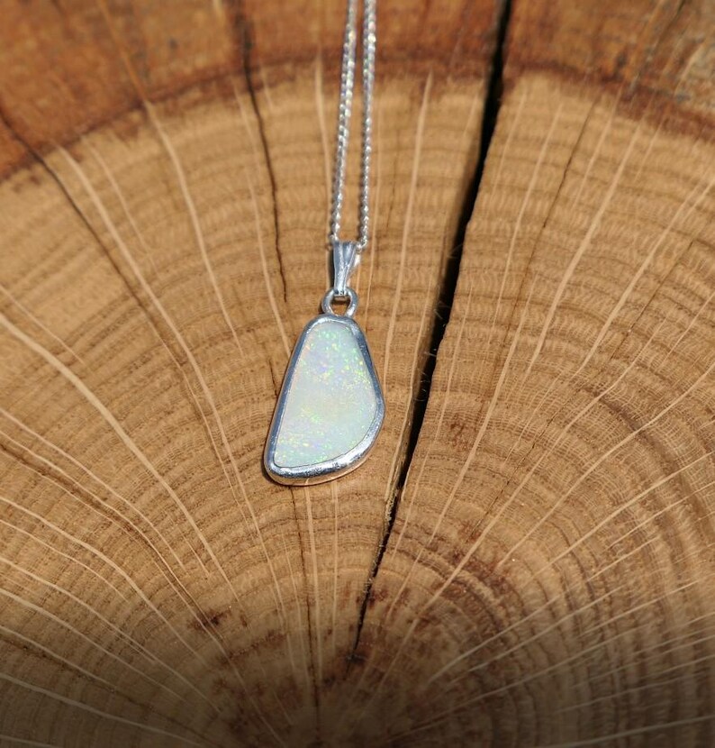 May include: A silver chain necklace with a white opal pendant. The pendant is a freeform shape and has a silver setting.