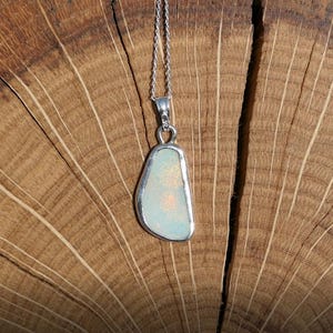 May include: A silver chain necklace with a pendant featuring a white opal stone set in a silver bezel.