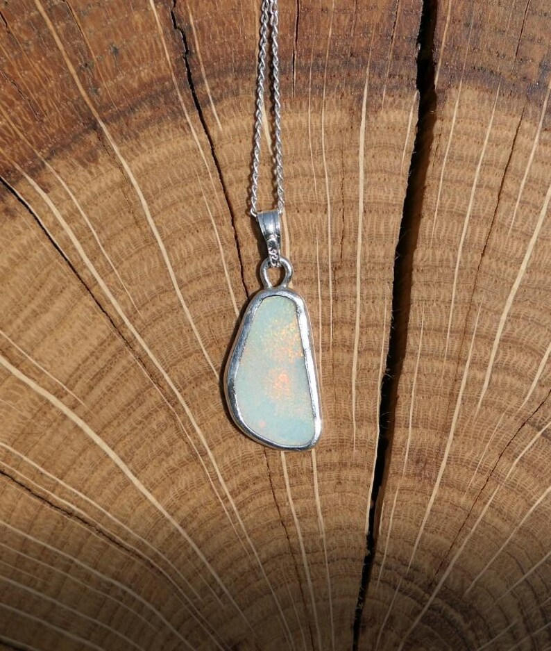 May include: A silver chain necklace with a pendant featuring a white opal stone set in a silver bezel.