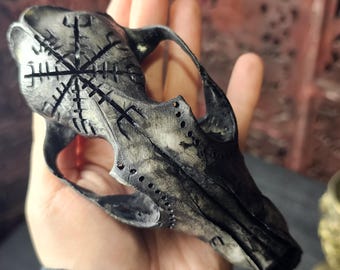 May include: A black and white animal skull with a carved compass design on the forehead. The skull is made of resin and has a distressed finish.