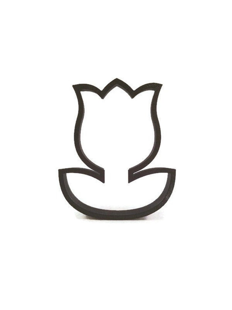 May include: A black tulip-shaped cookie cutter. The cutter is made of a dark material and has a simple outline of a tulip flower with a stem and leaves. The design is clean and minimalist, perfect for baking.