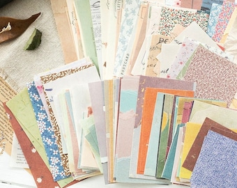 Könnte beinhalten: Eine Sammlung dekorativer Papierschnipsel in verschiedenen Farben und Mustern, darunter florale, geometrische und abstrakte Designs. Die Papiere sind fächerförmig angeordnet, wobei sich die Ränder der Papiere überlappen. Die Papiere sind alle unterschiedlich groß und geformt, und einige haben bedruckten Text, wie z. B. "POSTCARD" und "LATTE".