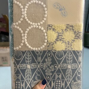 May include: A frosted matte PVC cover for a planner or notebook. The cover features a patchwork design with different patterns and textures, including a butterfly motif. The text "Frosted Matte PVC Cover" is printed at the bottom of the image.