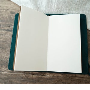 May include: An open, blank, green leather-bound journal with brown paper pages.