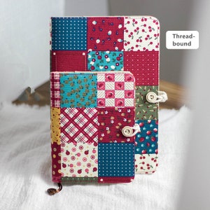 K&ouml;nnte beinhalten: Zwei Notizb&uuml;cher aus Patchwork-Stoff mit Knopfverschl&uuml;ssen. Das kleinere Notizbuch ist in das gr&ouml;&szlig;ere Notizbuch gelegt. Beide Notizb&uuml;cher haben eine Vielzahl von bunten Mustern, darunter Rot, Blau, Gr&uuml;n und Wei&szlig;. Der Text "Thread-bound" ist in der oberen rechten Ecke des Bildes sichtbar.