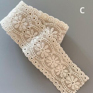 May include: A roll of off-white cotton lace trim with a delicate floral pattern. The lace has a scalloped edge and is perfect for adding a touch of elegance to any project.