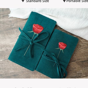 May include: Two green fabric journals with embroidered red roses and tied with green ribbon. The larger journal measures 22.2 inches by 12 inches and the smaller journal measures 18 inches by 10.8 inches.