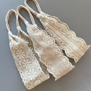 May include: Three beige fabric headbands with white lace trim. The headbands are made of a soft, stretchy fabric and have a delicate, feminine look.