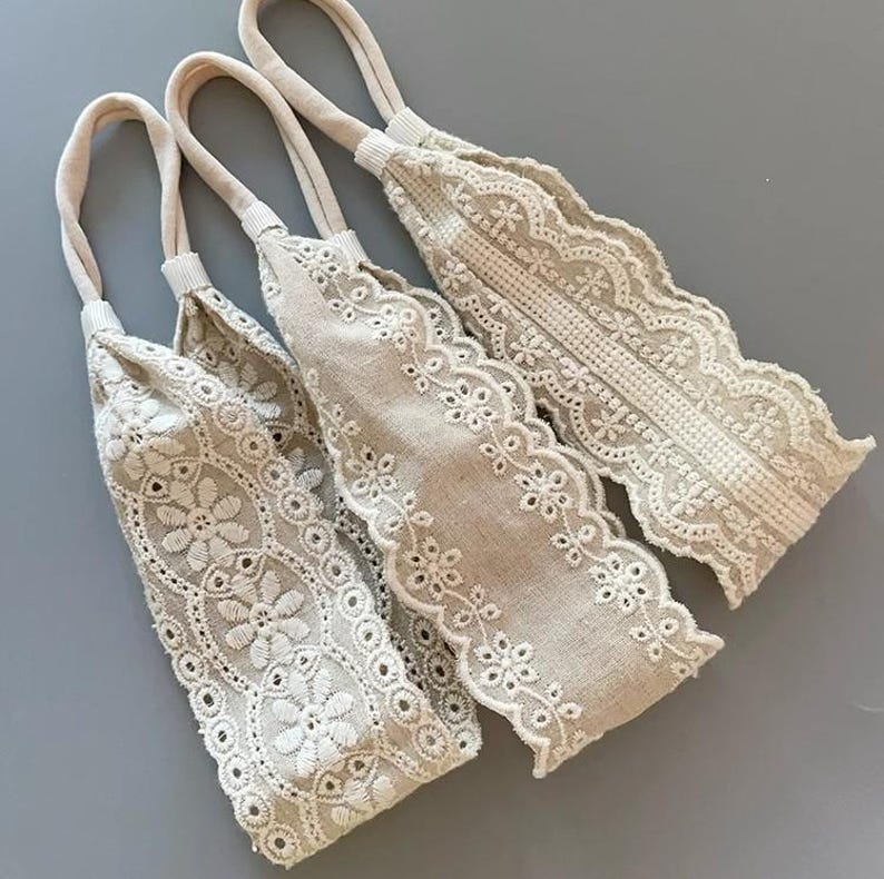 May include: Three beige fabric headbands with white lace trim. The headbands are made of a soft, stretchy fabric and have a delicate, feminine look.